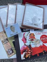 Lot overview showing Coca-Cola metal sign with Santa Claus and various photo frames in packaging and loose