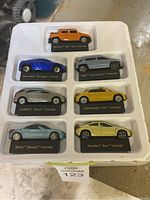 Packaged set of 7 GM concept vehicle miniature models in a white molded plastic holder, each on labeled stands.