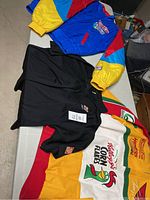 Three vintage racing coats and one racing shirt laid out flat on a table showing colors and logos.