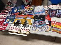 Table display of assorted NASCAR and other advertising signs, memorabilia and shirts