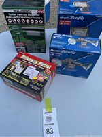 Lot items displayed on table showing all boxed items: Heath Zenith outdoor lights, Driveway Patrol alert system, Bell + Howell Solar Animal Repeller.