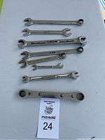 Seven Snap-On brand combination and box-end wrenches of various sizes displayed on a light-colored surface.