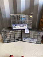Three black Strong N' Tuff utility cabinets each with 30 clear plastic drawers shrink wrapped together