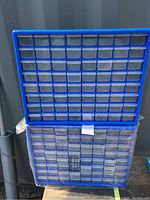 Photo showing two blue utility organizers stacked vertically, each configured with 64 small clear plastic drawers for item storage and sorting.