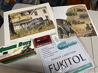 Photo showing Quaker State sprint car model in box, vintage Buick poster, Old Timers print, FUKITOL flyer, and a small red model car