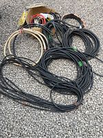 Various coils of black and white electrical wires laid out on gravel.