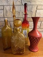 Group photo of 5 decorative pieces including 4 bottles and 1 vase on wood surface with stone background