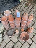 Photo showing several stacks of small to medium-sized, weathered terracotta pots on stone pavement