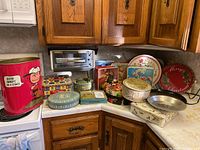 Overview of all 16 vintage tins, trays and Peanuts metal wastebin arranged on kitchen counter