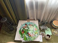 Overview of lot showing large birdcage, decorative butterfly glass suncatcher, two green glass bird feeders, ceramic flower pot with floral design, and small garden decor items.