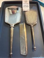 Hand mirror, hairbrush, and comb displayed on black tray