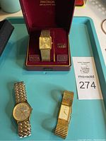 Three watches displayed on a tray: Bulova in presentation box with mesh band, Bulova round watch with expandable band, and Gruen quartz watch.