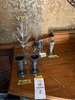Overall view of nine pieces on wooden surface, showing various candleholders and glassware with size markers.