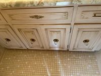 Wide shot of a distressed wooden cabinet with four brass pulls and two brass knobs mounted on doors. The cabinet shows signs of use and age.