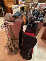 Wilson HT1000 golf clubs in bag with push cart and some accessories in surroundings, showing overall set and condition.