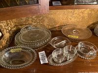 Photo showing multiple glass plates, bowls, and serving pieces with rounded bead edges typical of Imperial Candlewick glass.