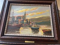 Full view of the oil painting showing harbor scene, wooden frame, and brass nameplate.