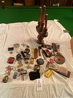 Full view of vintage miscellaneous collectibles including candle holder, pins, keychains, and souvenir items on a white cloth