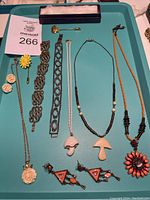 Full lot of vintage jewelry on turquoise background including mushroom necklaces, floral pins, carved flower pieces, bracelets, and earrings.