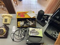 Overview of lot including vintage telephone, Braun Paximat 8mm projector in box, 800 Projector turntable, and cables.