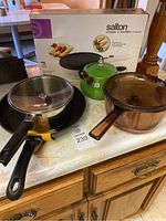 Overall view of 8 pieces including glass pans, a green kettle, covered pots, and boxed Salton crepe and tortilla maker.