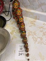 Photo showing all 10 Russian wooden nesting dolls lined up from largest to smallest on a floral patterned surface.