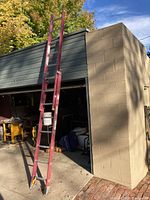 Full view of ladder leaning against the building showing the length and condition.