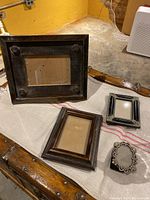 Four picture frames of various sizes displayed on a table with a textured cloth background.
