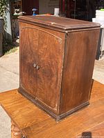 Full view of walnut burled cabinet showing front and side panel with door closed.