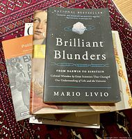 Stack of books including 'Brilliant Blunders' by Mario Livio and other titles, showing book covers and condition.