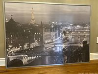 Front view of large black and white IKEA print of Paris night scene with Eiffel Tower, mounted in a black frame.