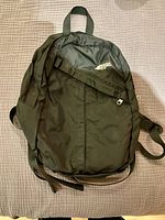 Small black MEC backpack with zippered front pocket and padded shoulder straps.
