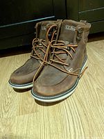 Brand new LL Bean brown leather boots size 9 with laces, sitting on wooden floor.