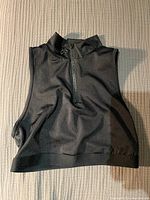 Black cropped sleeveless TNA bra/top with front zipper, laid flat showing details