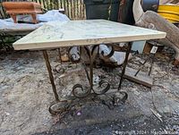 Side view of the antique side table showing the wrought iron twisted base and stone top.