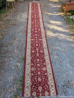 Full length view of the long floral runner rug laid on an outdoor ground surface showing its length and design.