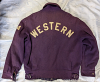 Photo of the back of the vintage purple wool varsity jacket displaying the "WESTERN" text and number "64" on the sleeve.