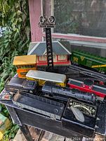 Photo showing multiple items in the vintage Marx O gauge train set lot including locomotive, rolling stock cars, buildings, transformer, signal light tower, and track pieces.