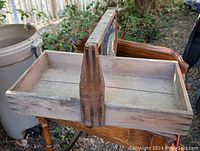Photo of the vintage wooden berry box carrier showing the full rectangular box with central handle and aged wood finish.
