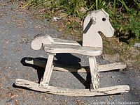 Side view of vintage white wooden kids rocking horse showing weathered paint and carved wood details