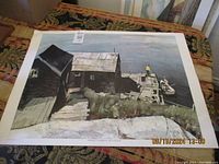 Photo shows one of the prints laid flat on a decorative surface depicting wooden fishing harbor buildings and docks with moored boats at Prospect Harbour, Nova Scotia.