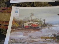 Photograph showing one of the dry dock boat scene prints, signed by Collin, with visible matting and partial price tag in corner.