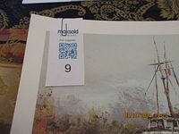 Close-up of one print showing the art of a dock scene and the paper with minor edge wear on the white matting.