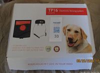Box top with TP16 electronic fencing system branding, showing product image and dog photo