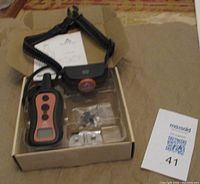 Full kit in original packaging box showing the remote control, collar, two sets of contact points and instruction manual.