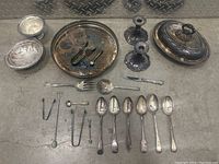 Full lot overview showing all silver cutlery and decorative items arranged on floor.