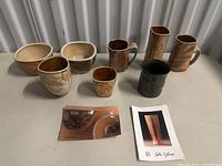 Overview of the lot showing bowls, mugs, and small cups with different glaze patterns on a flat surface.