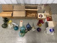 Nine ornaments arranged on floor in front of packaging boxes