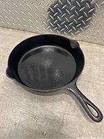Front and interior view of the Griswold cast iron skillet showing smooth cooking surface and dual pour spouts.