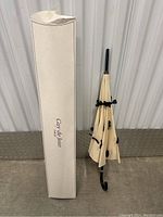 Closed umbrella with cream fabric canopy and black bows next to its original Guy De Jean Paris box.